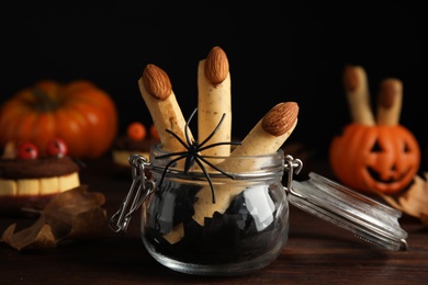 Photo of Delicious desserts decorated as monster fingers on wooden table. Halloween treat