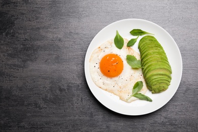 Photo of Tasty breakfast with fried egg and avocado on grey table, top view. Space for text