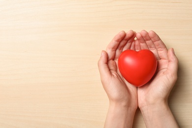 Photo of Woman holding heart on wooden background, top view with space for text. Donation concept