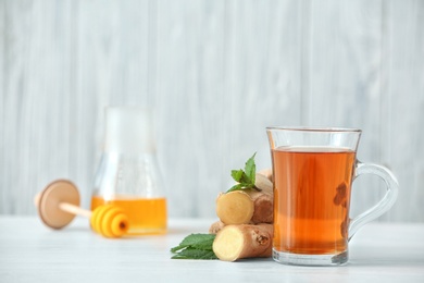 Photo of Cup of tea, mint and ginger on table. Space for text
