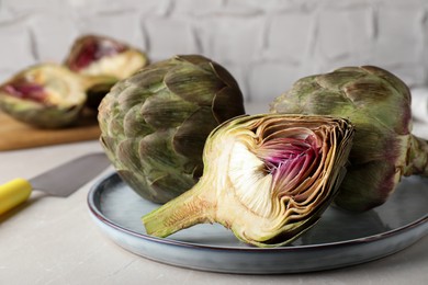 Photo of Cut and whole fresh raw artichokes on table