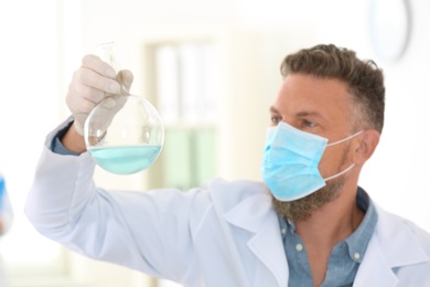 Photo of Male scientist with protective mask working in laboratory. Research and analysis