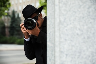 Photo of Private detective with modern camera spying on city street