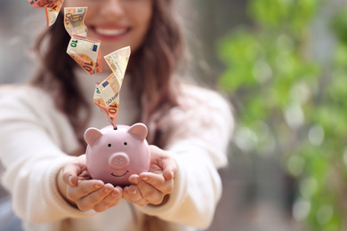 Image of Woman with piggy bank indoors, closeup. Space for text