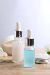 Photo of Bottles of cosmetic serum on wooden table