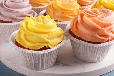Photo of Tasty colorful cupcakes with cream on marble stand, closeup