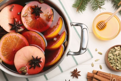 Photo of Delicious mulled wine and ingredients on white wooden table, flat lay