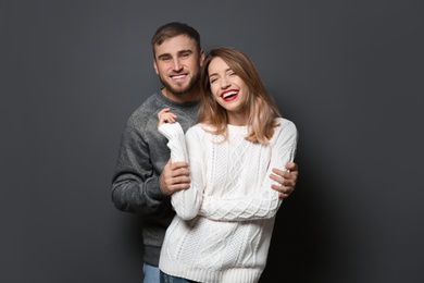 Photo of Young couple in warm sweaters on dark background