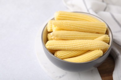 Photo of Tasty fresh yellow baby corns in bowl on white table, space for text