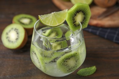 Photo of Glass of refreshing drink with cut kiwi on wooden table, closeup