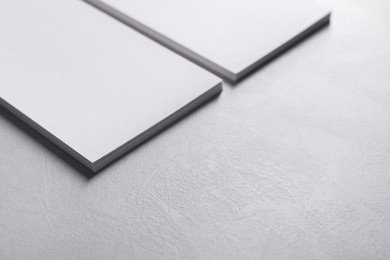 Photo of Blank business cards on light grey textured table, closeup. Mockup for design