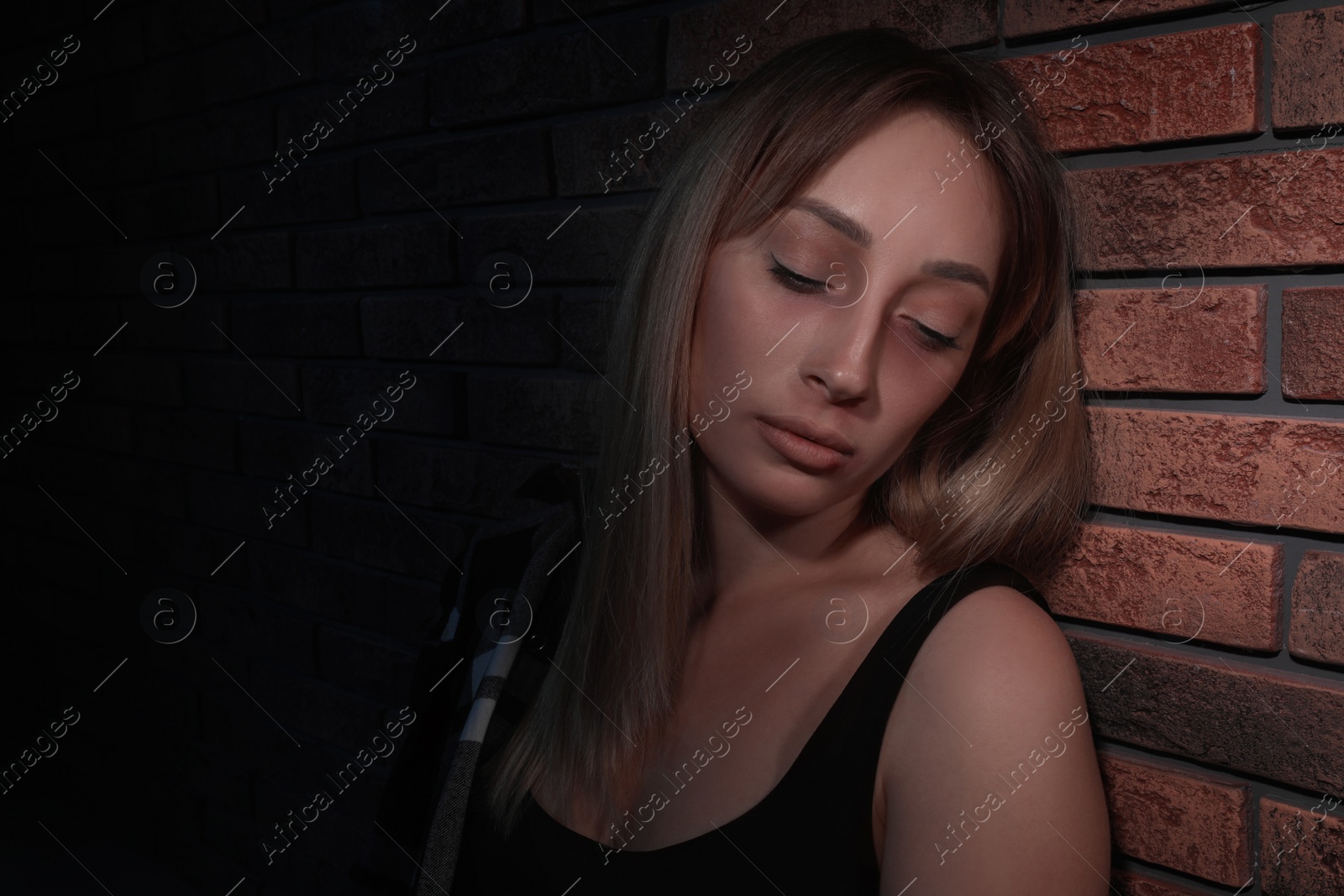 Photo of Overdosed drug addicted woman near brick wall