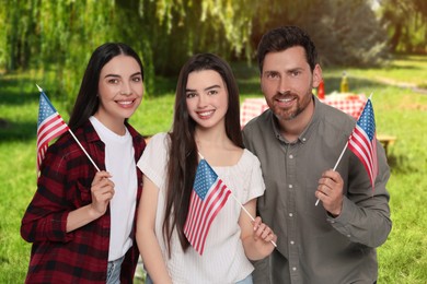 Image of 4th of July - Independence day of America. Happy family with national flags of United States having picnic in park
