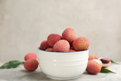 Photo of Fresh ripe lychee fruits in bowl on light grey table