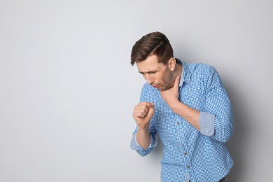 Photo of Young man coughing on light background