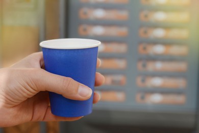Photo of Woman holding paper cup with coffee near vending machine, closeup. Space for text