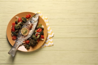 Photo of Delicious baked fish and vegetables on yellow wooden table, top view. Space for text