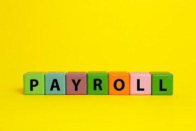 Photo of Colorful cubes with word Payroll on yellow background