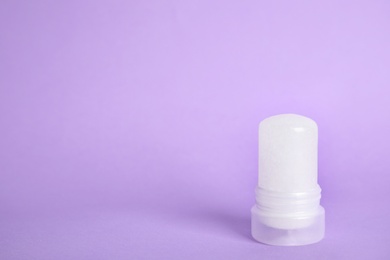 Photo of Natural crystal alum stick deodorant on lilac background. Space for text