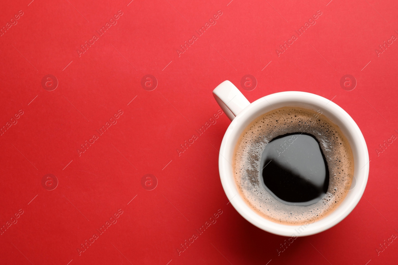 Photo of Fresh coffee in cup on red background, top view. Space for text