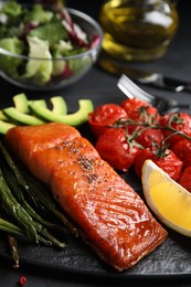 Photo of Tasty cooked salmon and vegetables served on black table, closeup. Healthy meals from air fryer