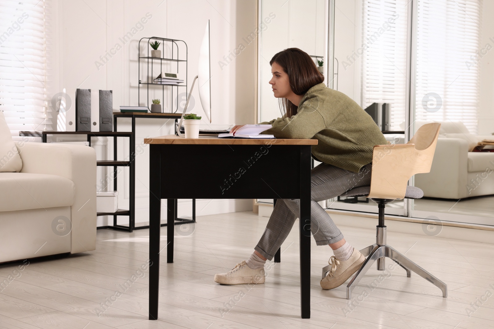 Photo of Young woman with bad posture working at table in office