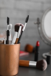 Holder with makeup brushes on table