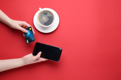 Photo of Online payment. Woman with smartphone, credit card and coffee on red background, top view. Space for text