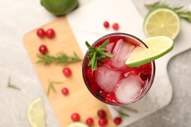 Photo of Tasty cranberry cocktail with rosemary and lime in glass on table, top view