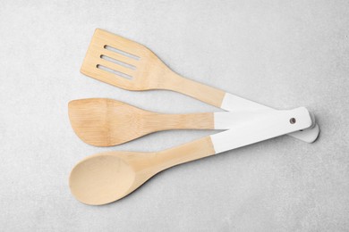 Photo of Set of wooden cooking utensils on light grey table, flat lay