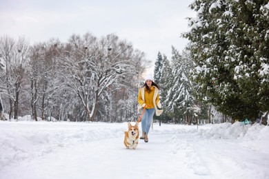 Photo of Woman with adorable Pembroke Welsh Corgi dog running in snowy park