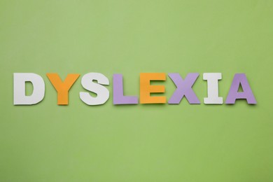 Photo of Word Dyslexia made of paper letters on light green background, flat lay