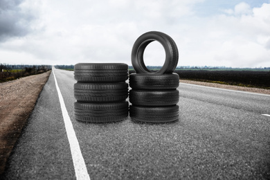 Image of Stacks of car tires on asphalt highway outdoors