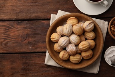Photo of Delicious nut shaped cookies with boiled condensed milk and powdered sugar on wooden table, flat lay. Space for text
