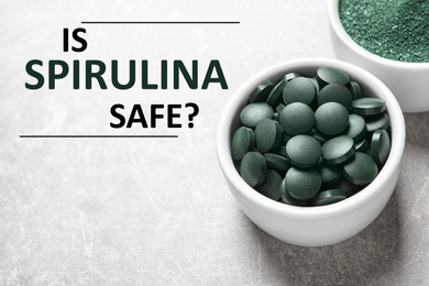 Image of Bowls of spirulina pills and powder on grey background. Side effects 