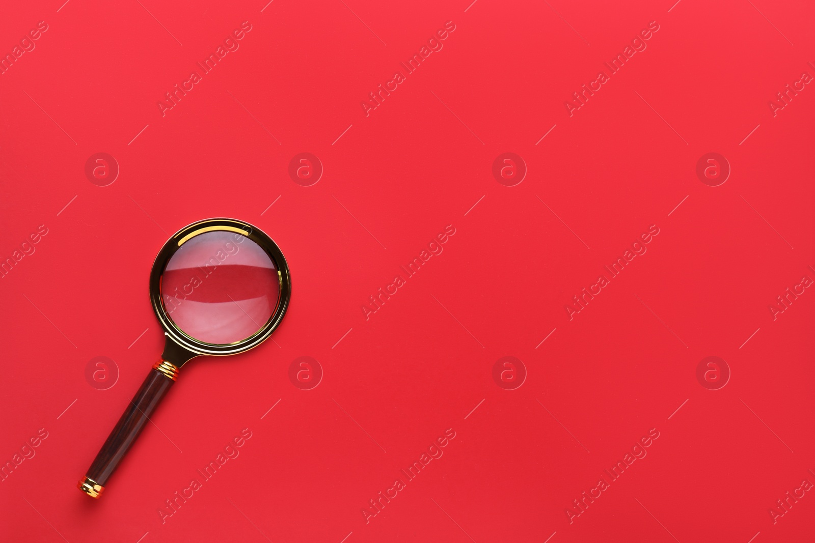 Photo of Magnifying glass on red background, top view. Space for text