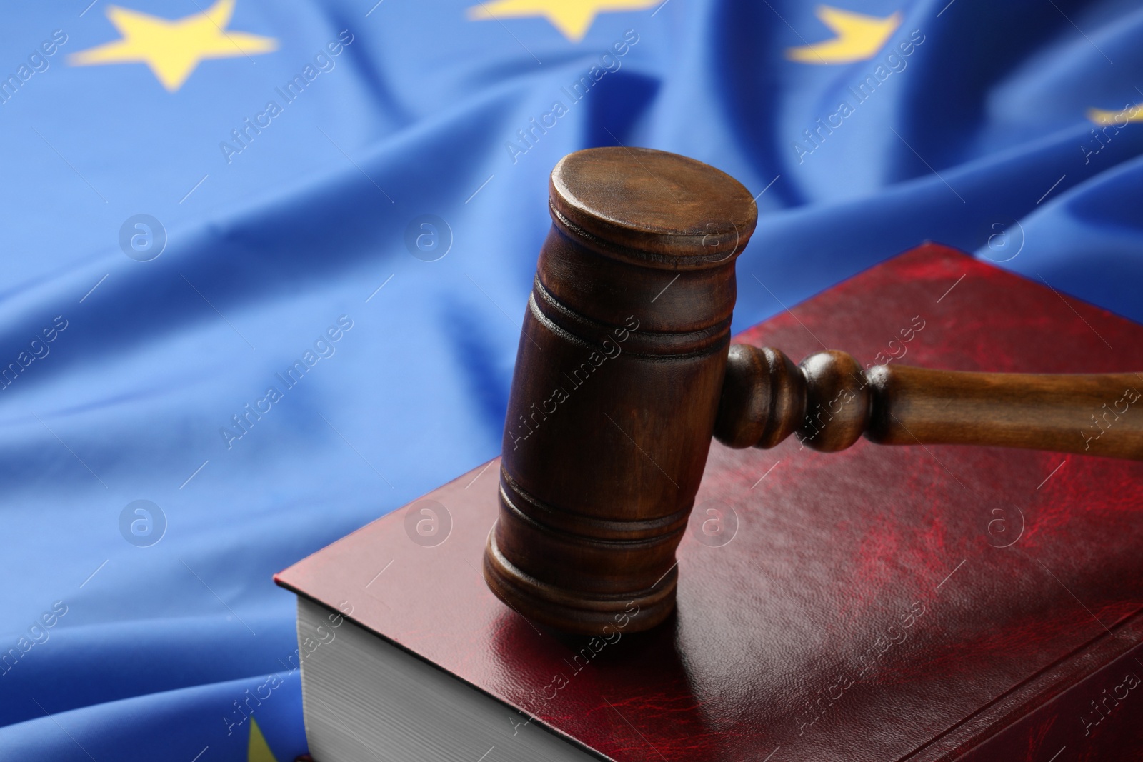 Photo of Wooden judge's gavel and book on flag of European Union, closeup. Space for text