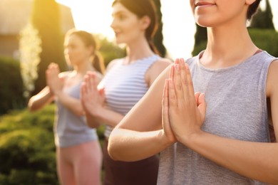 Photo of Young women practicing yoga outdoors on sunny day, closeup