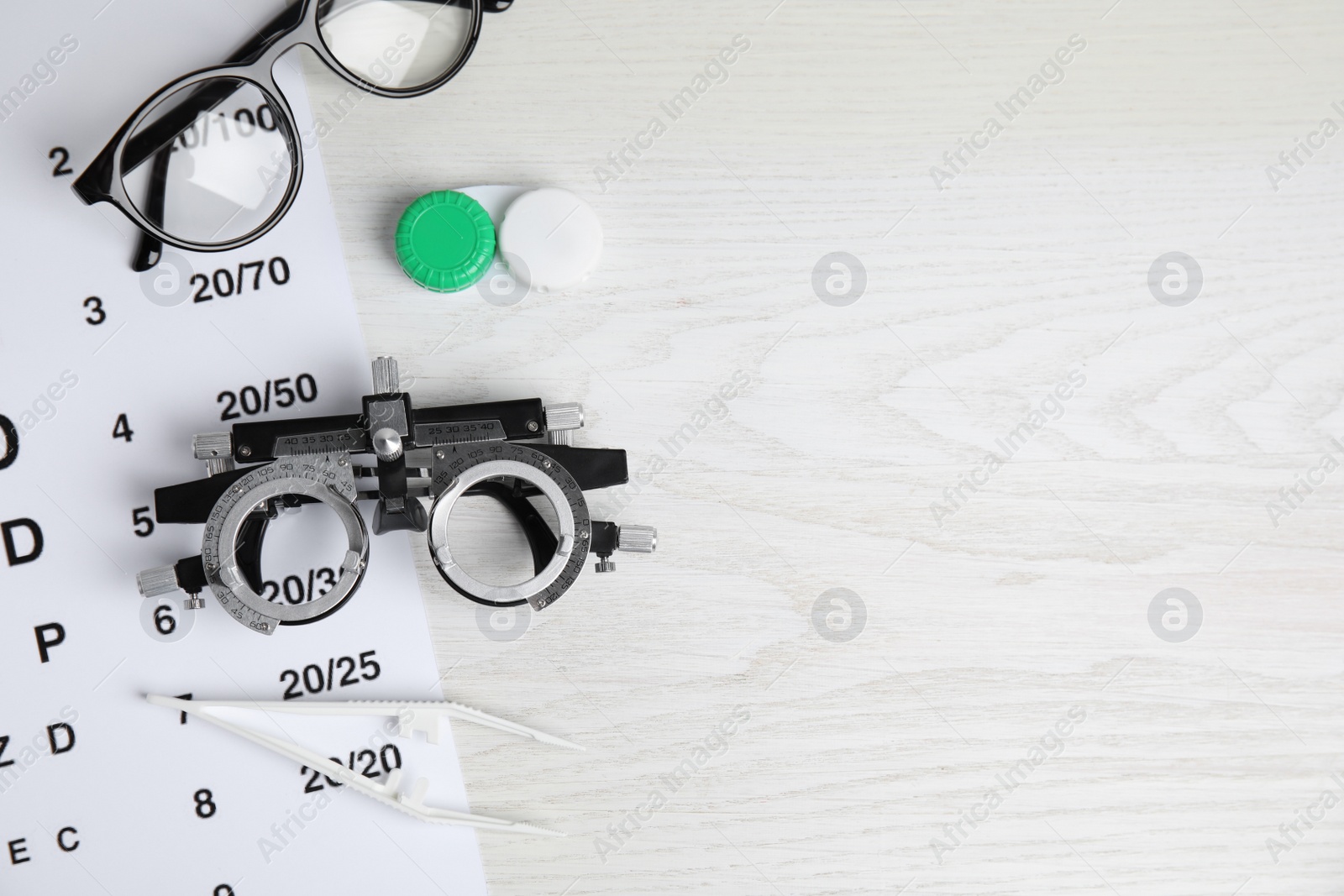 Photo of Different ophthalmologist tools on white wooden background, flat lay. Space for text