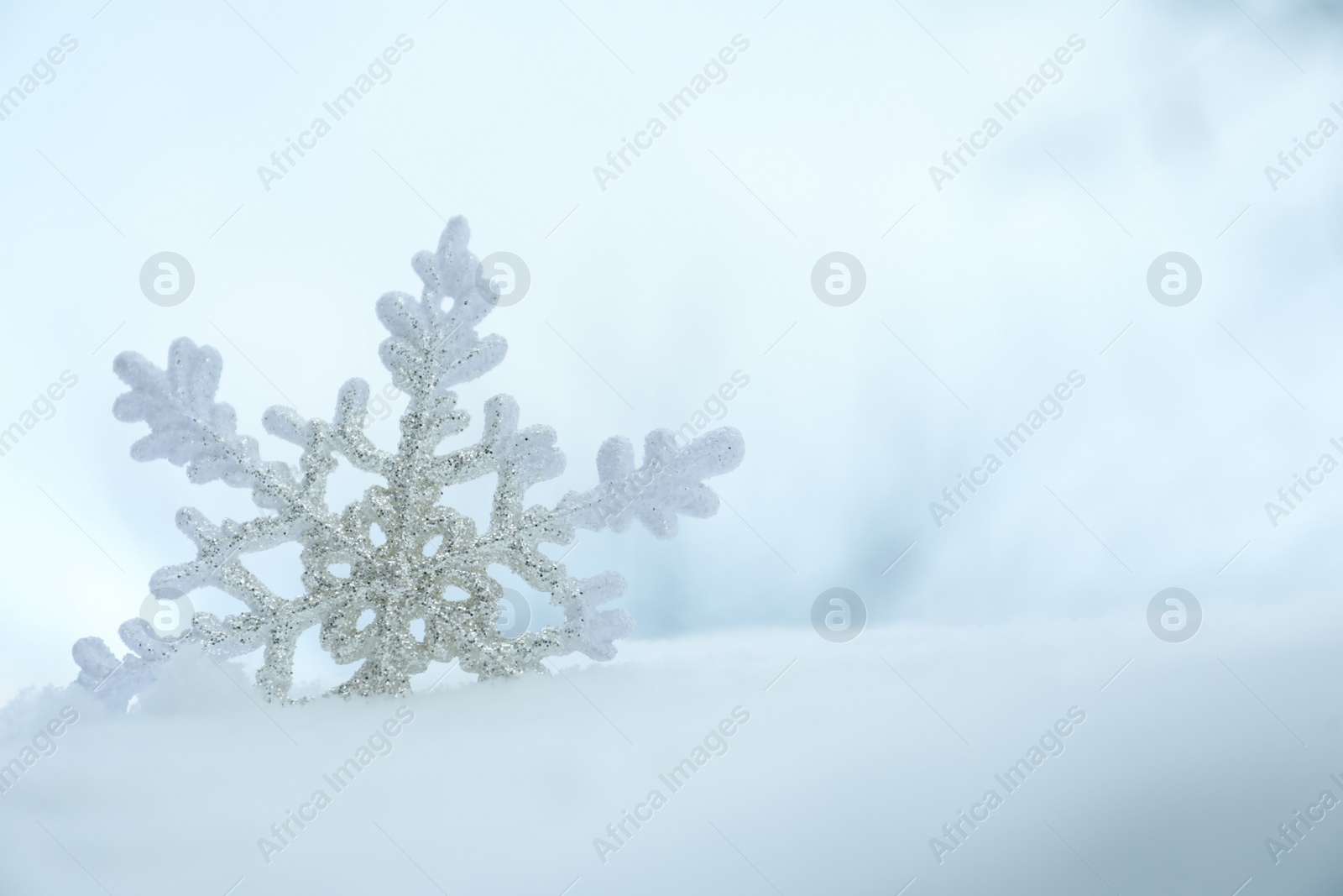 Photo of Beautiful decorative snowflake in white snow, outdoors. Space for text