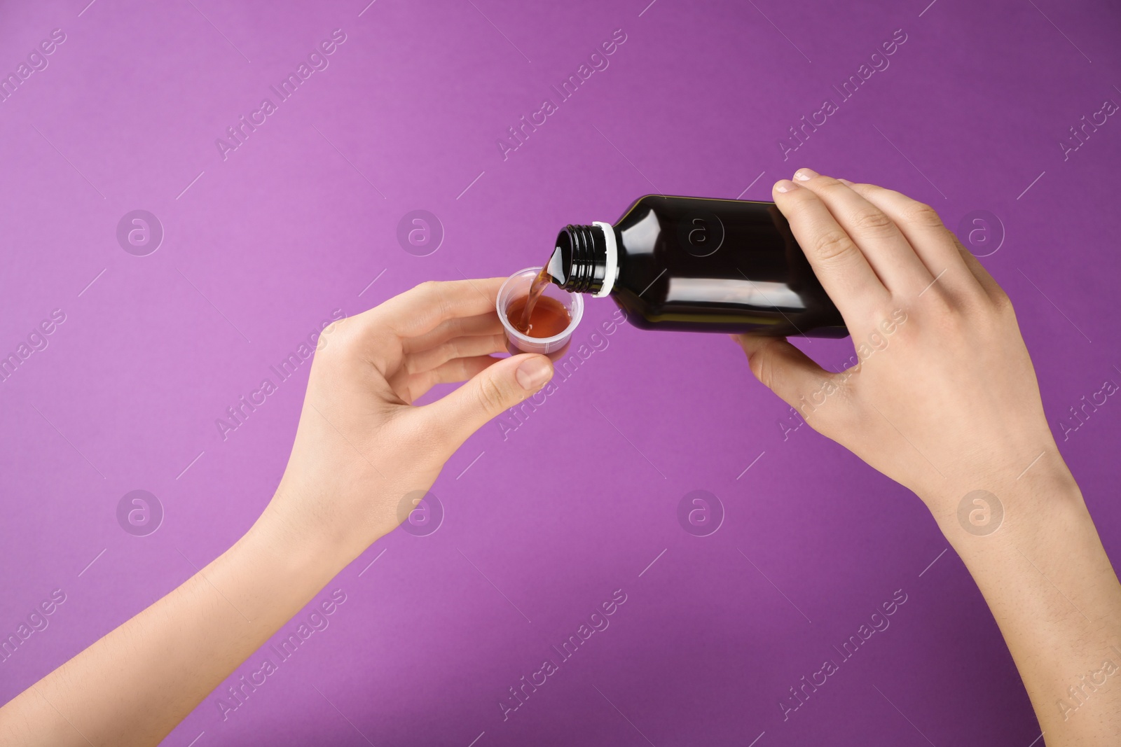 Photo of Woman pouring cough syrup into measuring cup on purple background, closeup