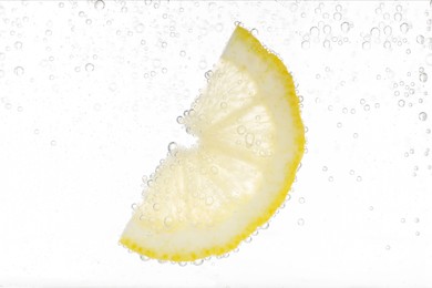 Juicy lemon slice in soda water against white background, closeup