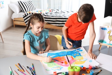 Photo of Little children painting picture at table indoors