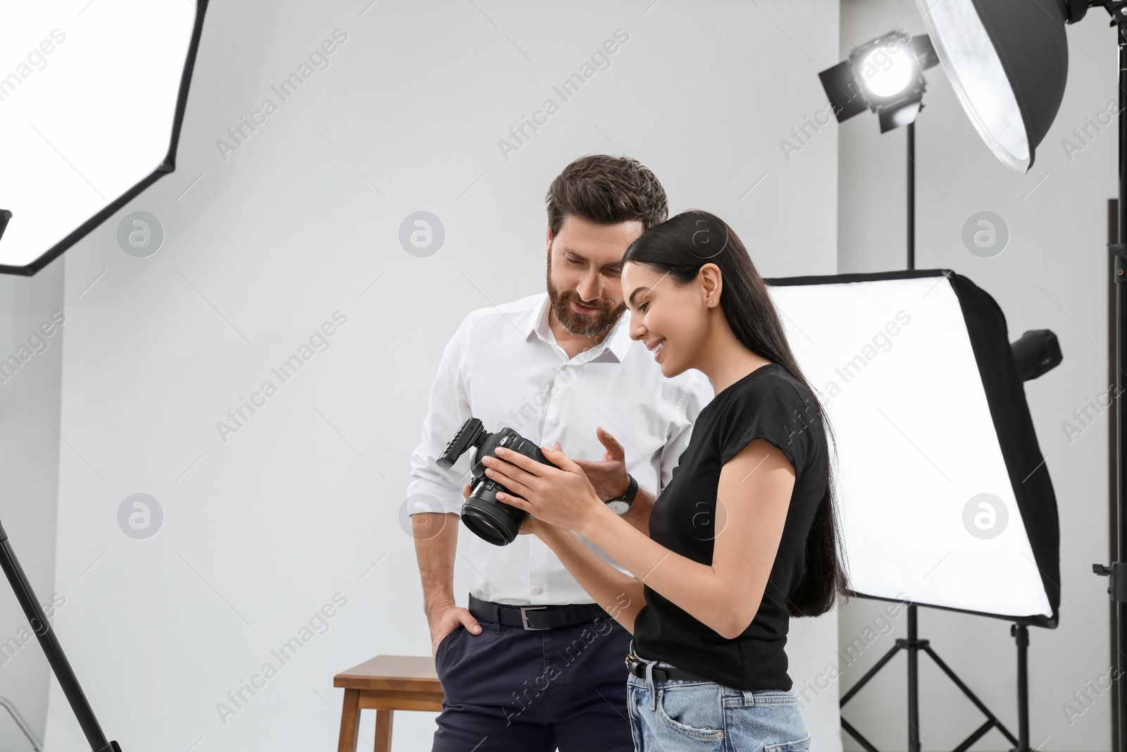 Photo of Professional photographer and model looking at pictures on camera in modern studio