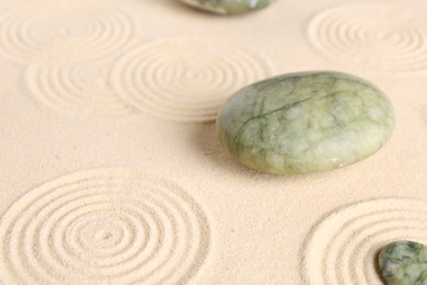 Photo of Zen garden stones on beige sand with pattern, closeup