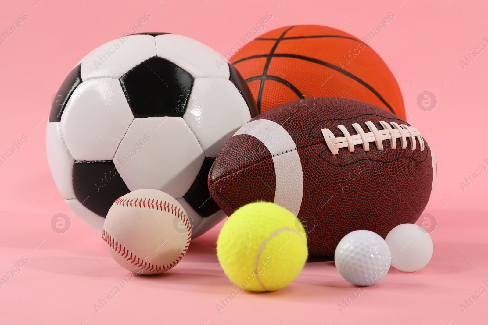 Photo of Many different sports balls on pink background