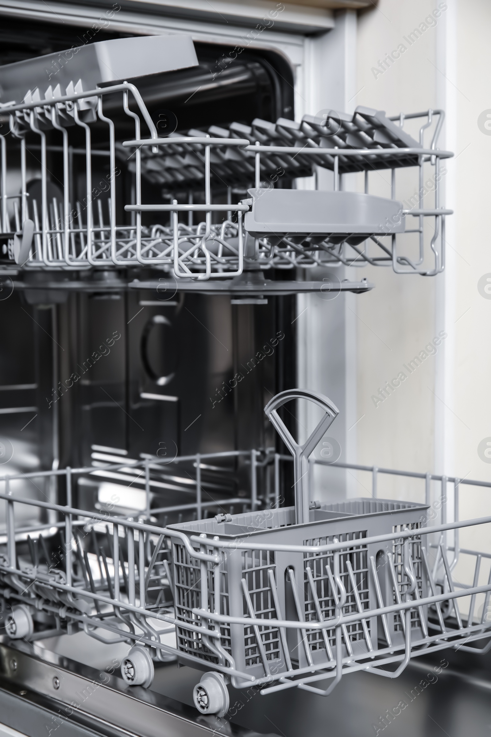 Photo of Open clean empty dishwasher in kitchen, closeup