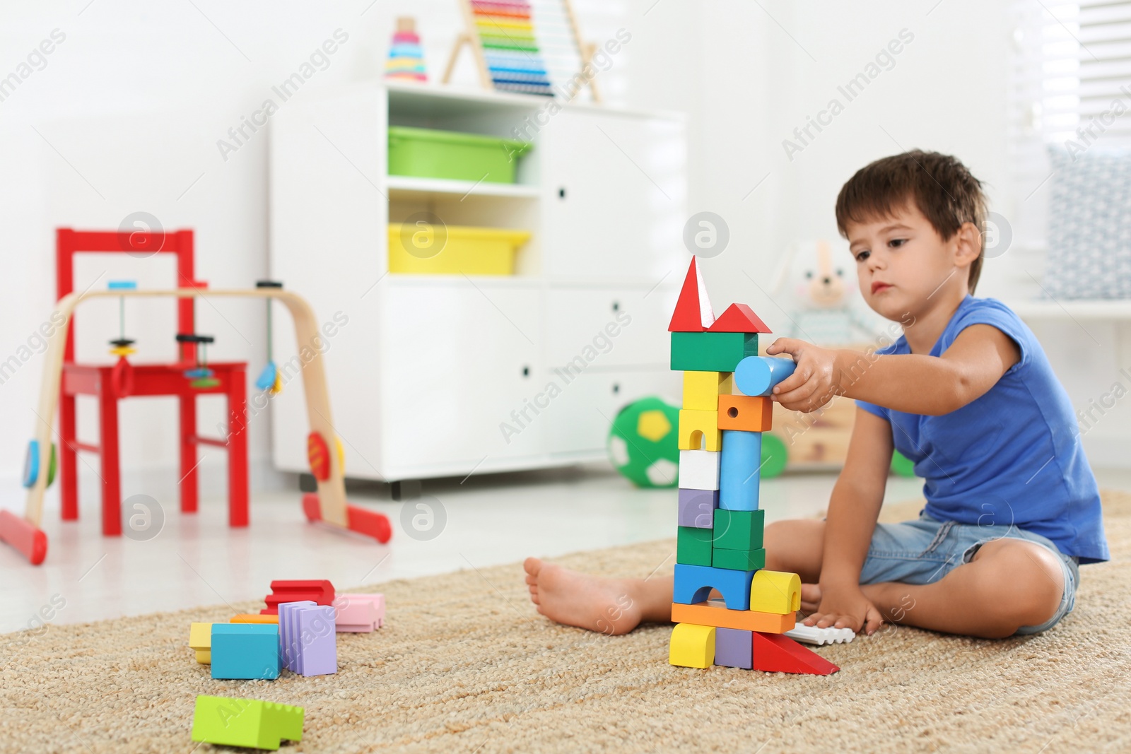 Photo of Cute little boy playing with colorful blocks on floor at home. Educational toy