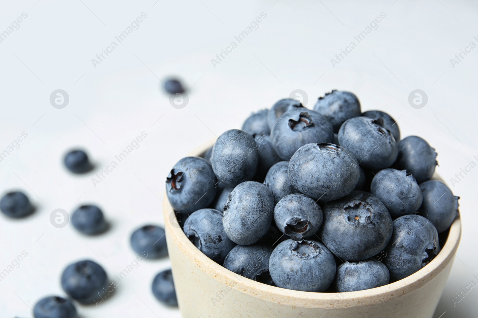 Photo of Crockery with juicy and fresh blueberries on white table, closeup