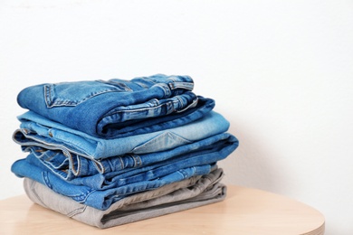 Stack of different jeans on table against white background. Space for text